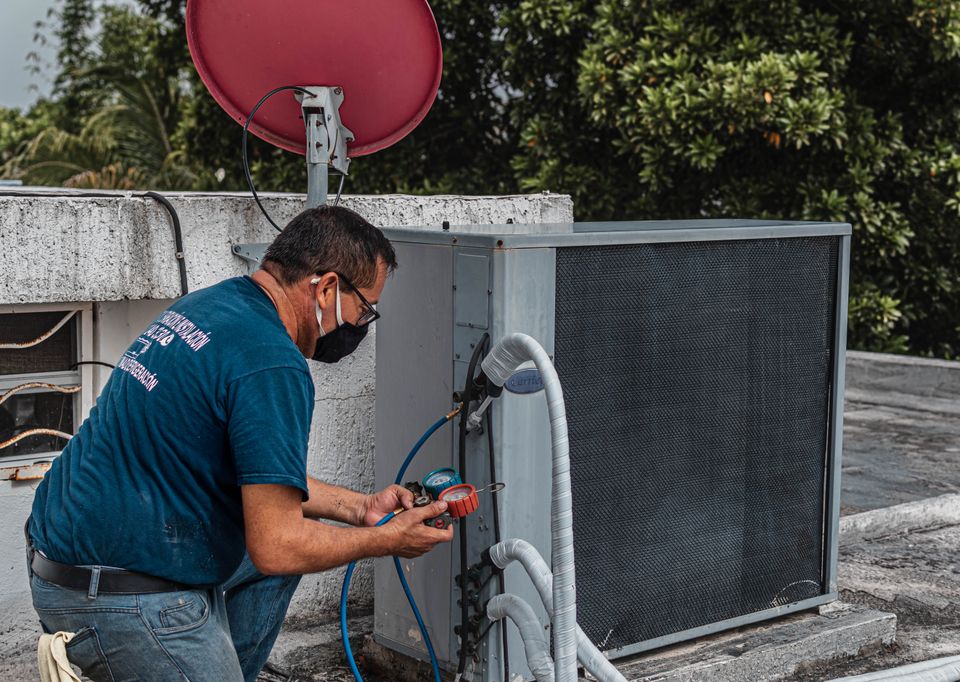 Technician using pressure gauges to diagnose an outdoor air conditioning unit