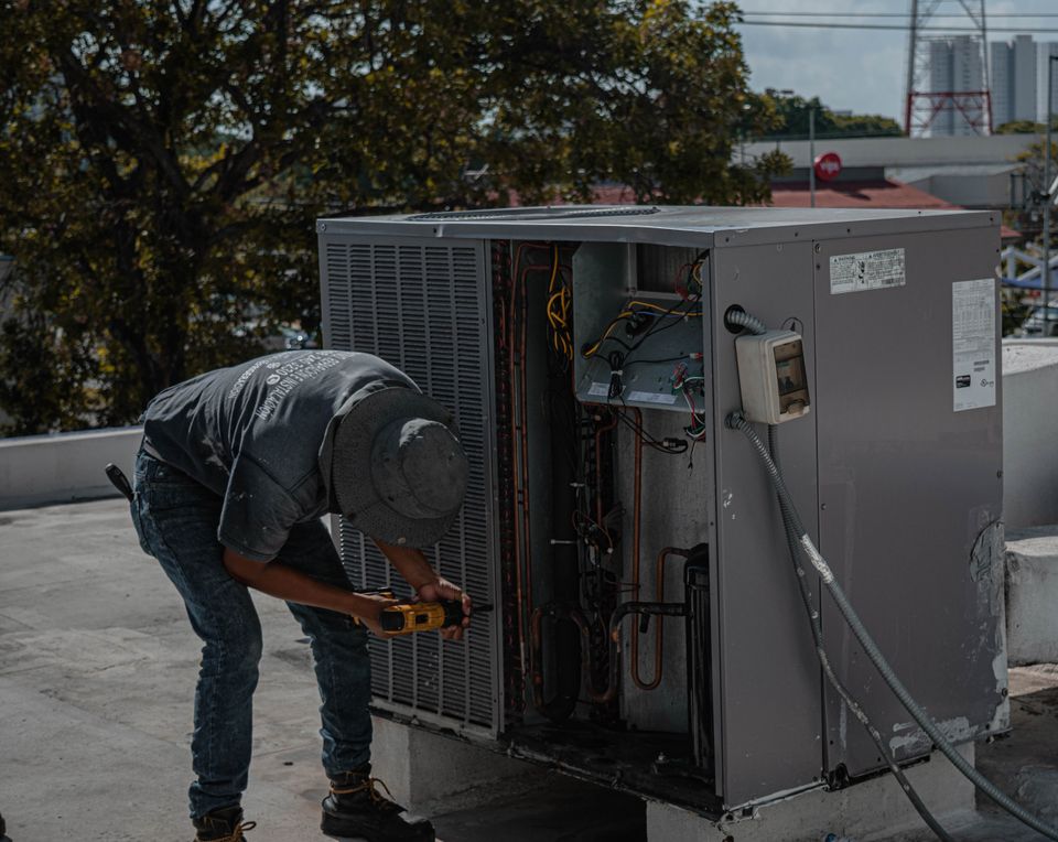 Technician installing and wiring a new packaged HVAC unit on a rooftop